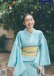 A woman in a blue kimono smiles at the camera.