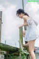 A woman in a white dress standing on a wooden dock.