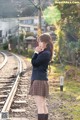 A woman in a school uniform standing on a train track.