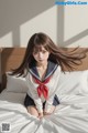 A woman in a sailor outfit sitting on a bed.