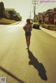 A woman walking down the middle of a street.
