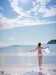 A woman standing on a beach with her arms outstretched.