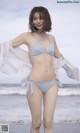 A woman in a blue bikini standing on a beach.