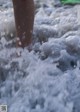 A person standing in the water with their feet in the waves.