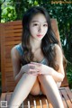 A woman sitting on top of a wooden bench.