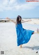 A woman in a blue dress is standing in the water.