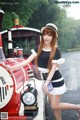 A woman in a black and white dress and hat standing next to a train.