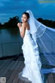 A woman in a wedding dress standing on a dock.